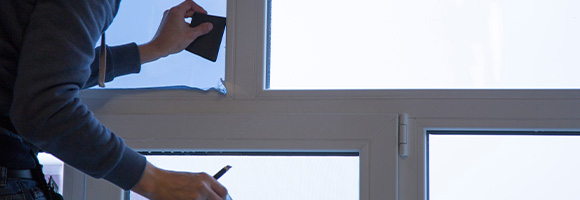person applying film to window with tools and pencil for window tinting 4 tips for better results