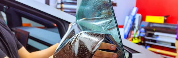 person applying a window film to a car door with a focus on precision and technique demonstration in a shop for optimizing 6 window applications
