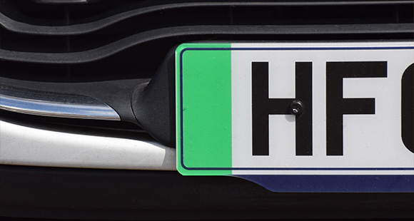 car front view with green license plate displaying HF and black lettering showcasing vehicle registration number