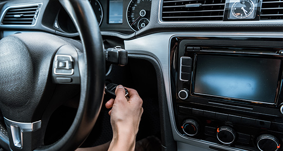 person inserting car key into ignition with dashboard visible modern vehicle interior automotive features